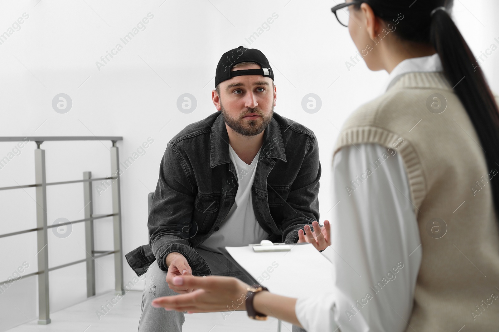 Photo of Psychotherapist working with drug addicted young man indoors
