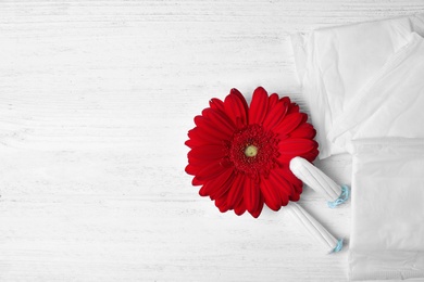 Photo of Different feminine hygiene products and flower on white wooden background, flat lay with space for text. Gynecological care