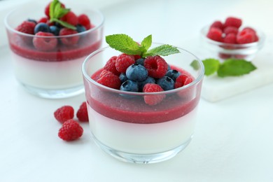 Photo of Delicious panna cotta with berries on white table