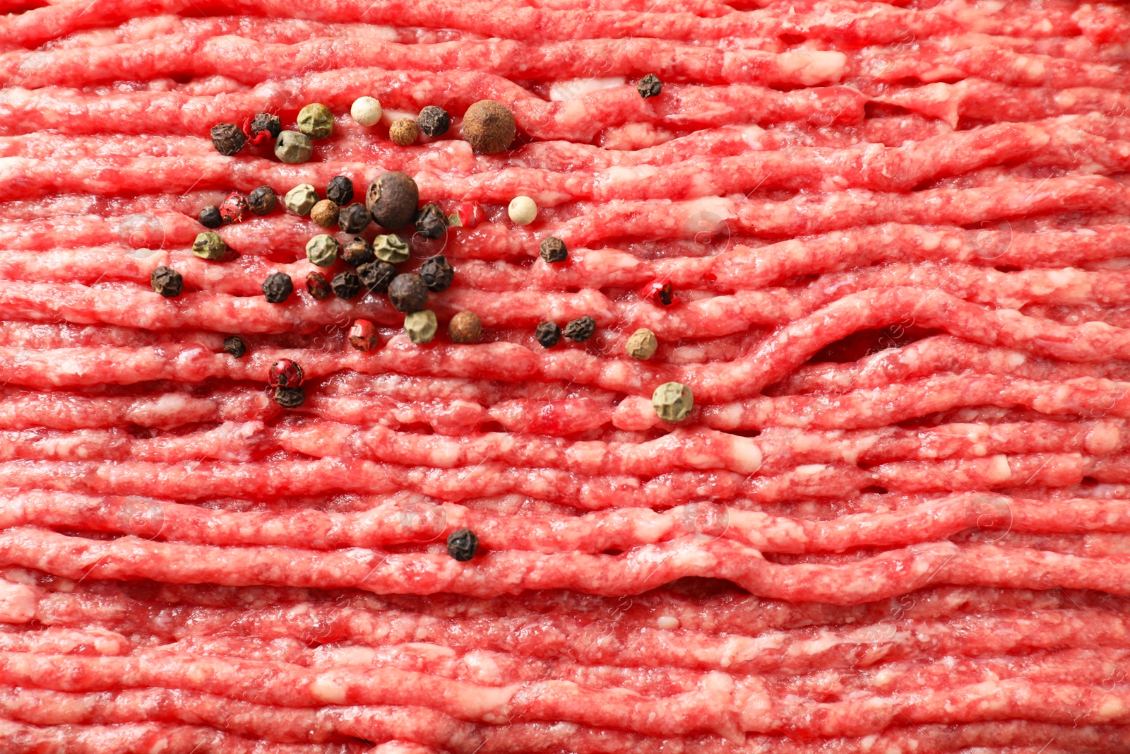 Photo of Raw ground meat and peppercorns as background, closeup