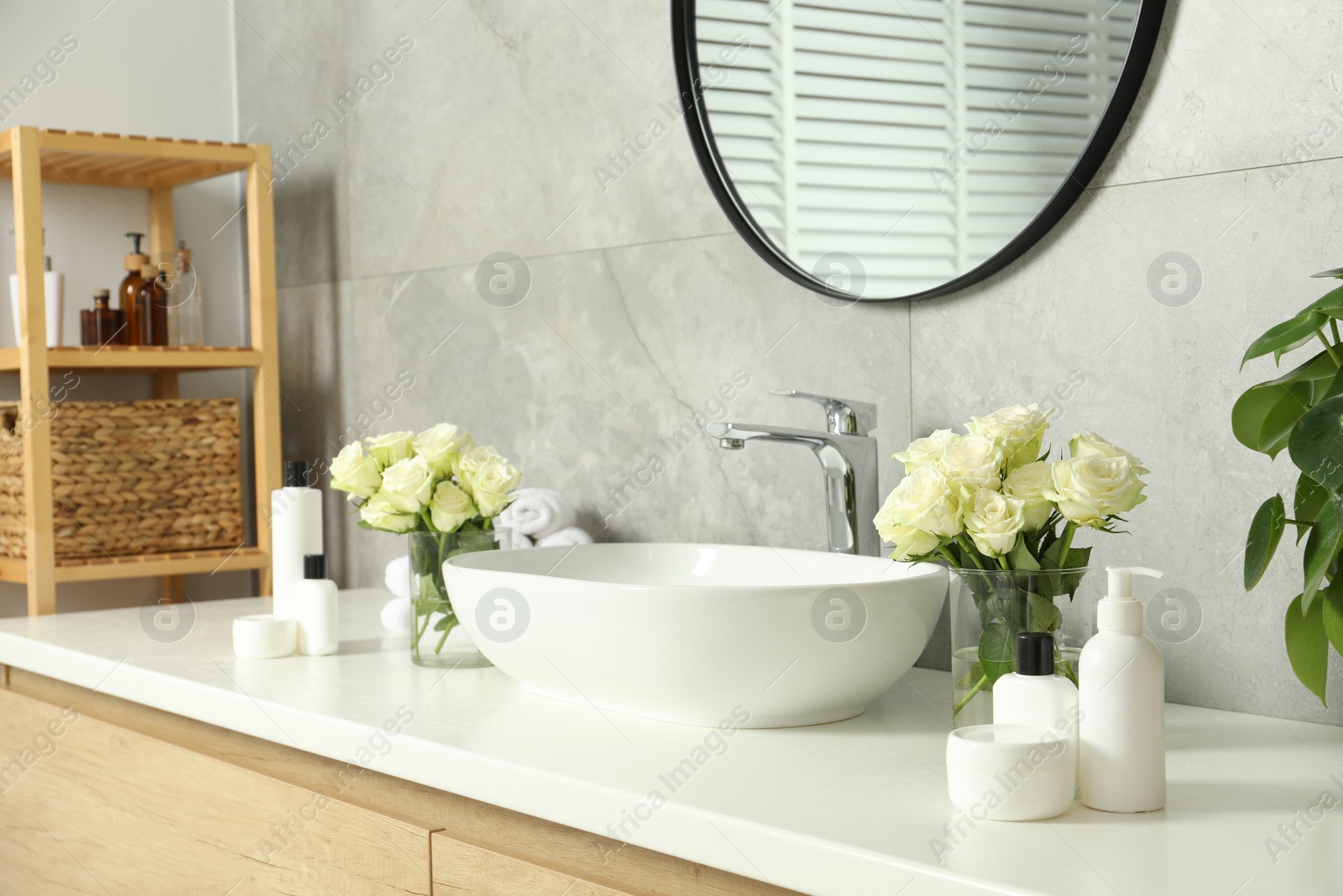 Photo of Beautiful roses and bath accessories near sink in bathroom