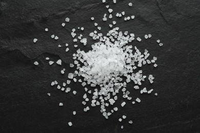 Photo of Pile of natural sea salt on black table, flat lay