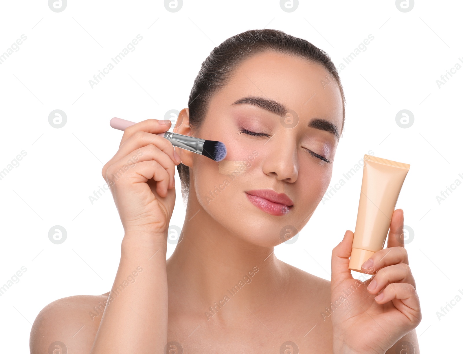 Photo of Woman with tube applying foundation on face using brush against white background