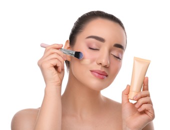 Photo of Woman with tube applying foundation on face using brush against white background