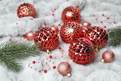 Photo of Beautiful Christmas baubles and fir tree branches on white fur