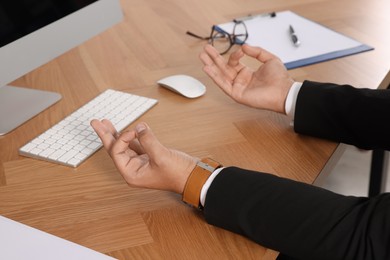 Businessman meditating at workplace, closeup. Zen concept