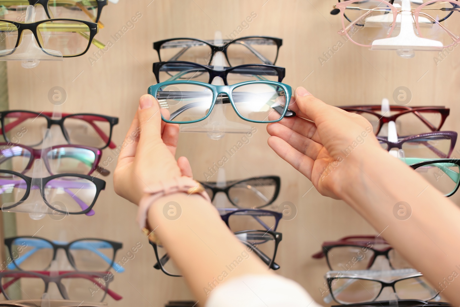 Photo of Female ophthalmologist taking glasses from showcase in optical store