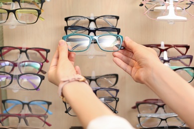 Female ophthalmologist taking glasses from showcase in optical store