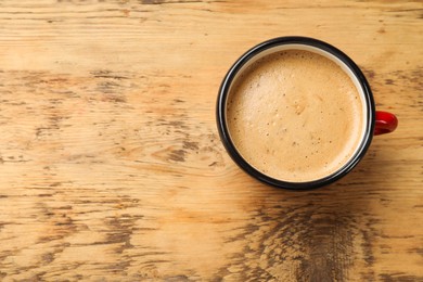 Photo of Cup of aromatic coffee on wooden table, top view. Space for text