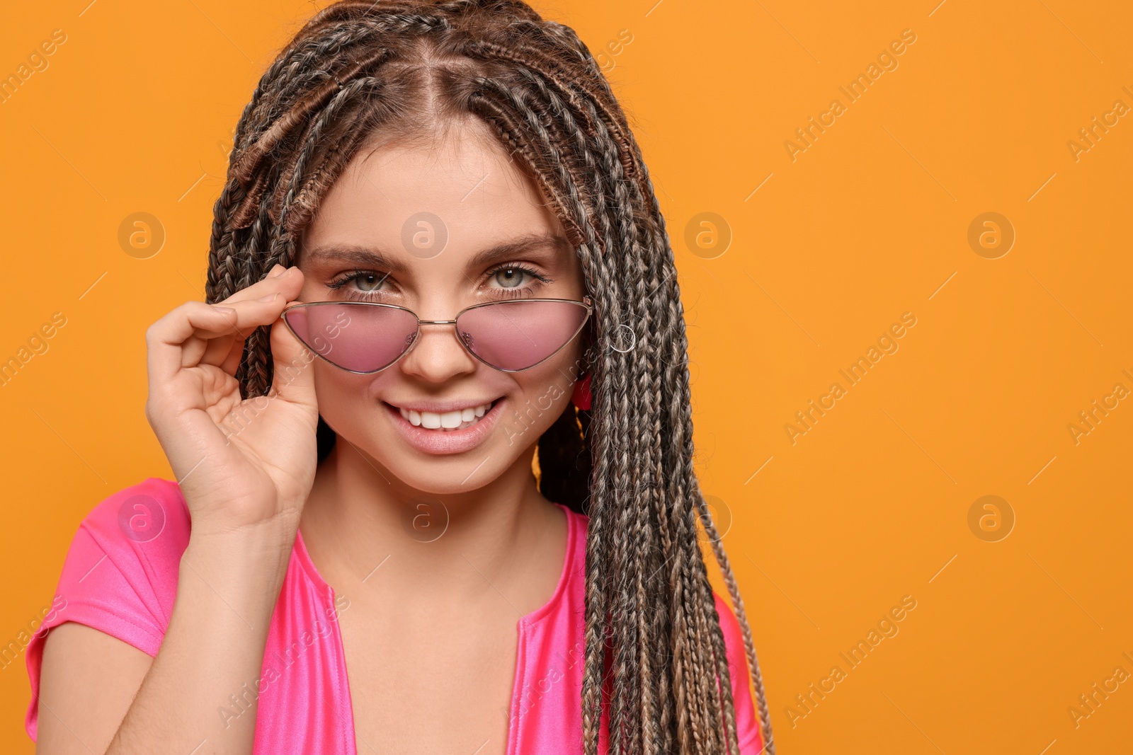 Photo of Beautiful woman with long african braids on yellow background, space for text