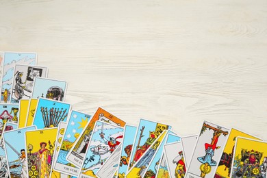 Photo of Tarot cards on white wooden table, top view. Space for text