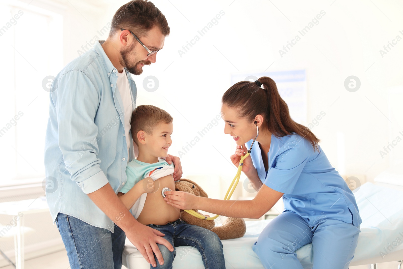 Photo of Children's doctor examining little boy with stethoscope in hospital