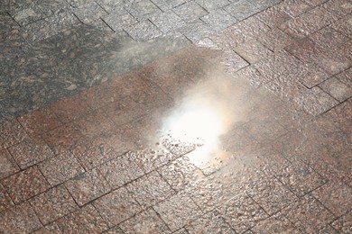 Photo of One puddle on street tiles outdoors after rain