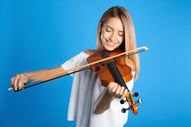 Photo of Beautiful woman playing violin on blue background