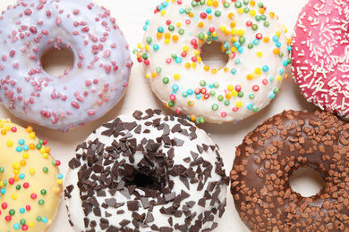 Photo of Delicious glazed donuts on white wooden table, flat lay