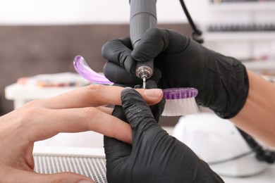 Photo of Professional manicurist working with client in salon, closeup