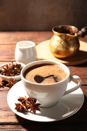 Cup of aromatic hot coffee with anise stars on wooden table