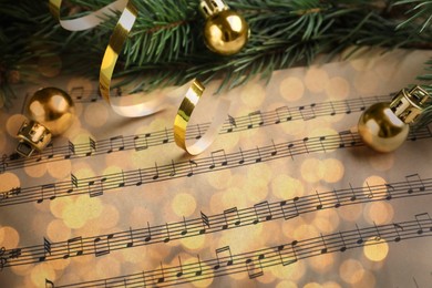 Image of Christmas and New Year music. Fir tree branch and festive decor on music sheets, bokeh effect