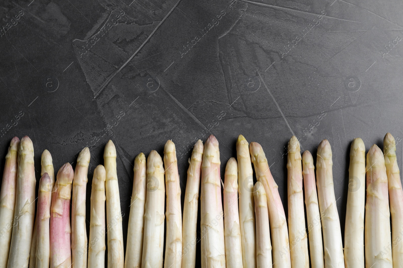 Photo of Fresh white asparagus on black table, flat lay. Space for text