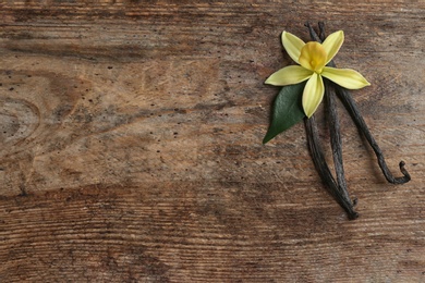 Flat lay composition with vanilla sticks and flower on wooden background. Space for text