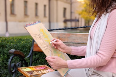 Woman drawing with soft pastels on bench outdoors, closeup