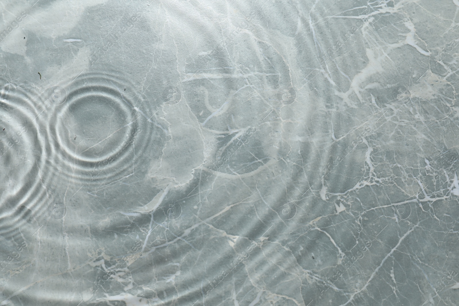 Photo of Rippled surface of clear water on light grey textured background, top view