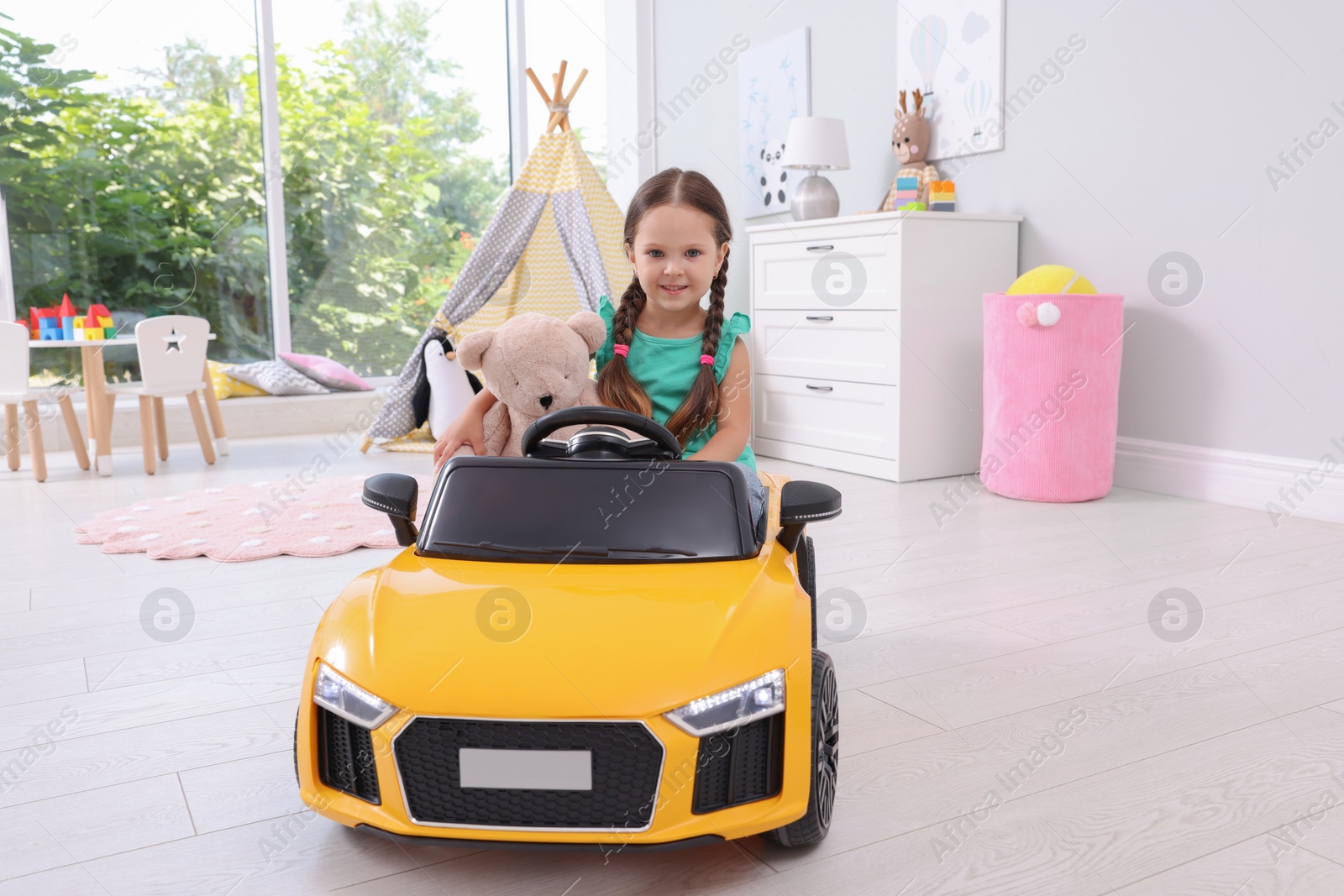 Photo of Adorable child with toy driving car in room at home