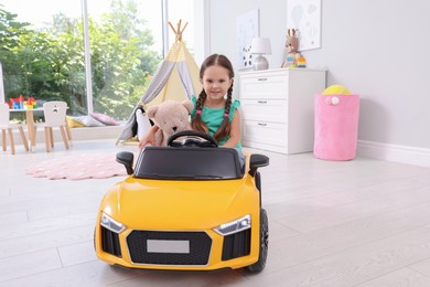 Adorable child with toy driving car in room at home