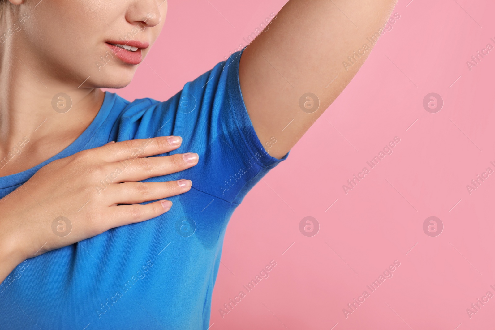 Photo of Young woman with sweat stain on her clothes against pink background, closeup. Using deodorant