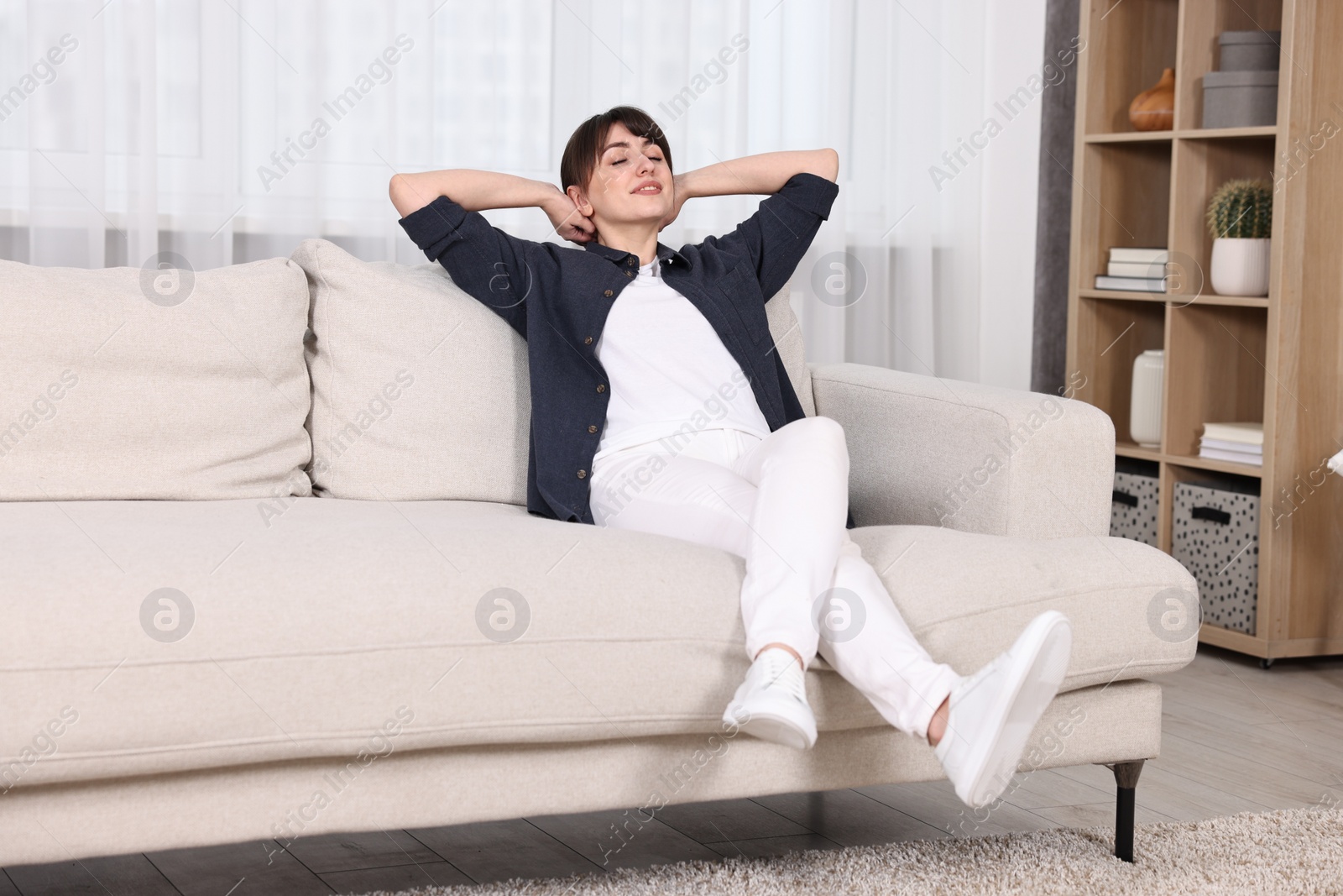 Photo of Beautiful young housewife resting on sofa at home