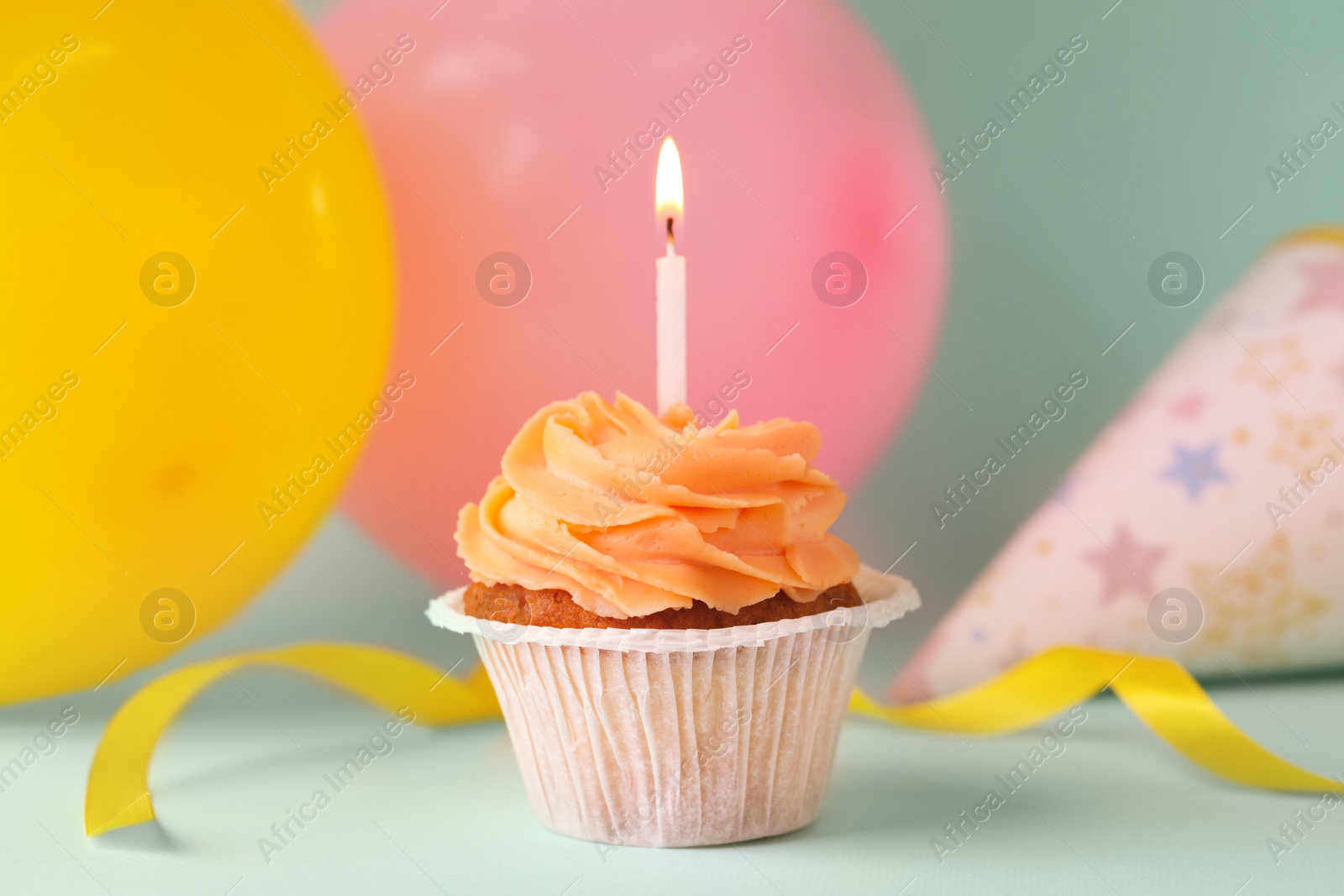 Photo of Tasty birthday cupcake with candle and party accessories on light blue table. Space for text