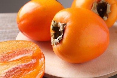 Photo of Whole and cut delicious ripe persimmons on wooden table, closeup