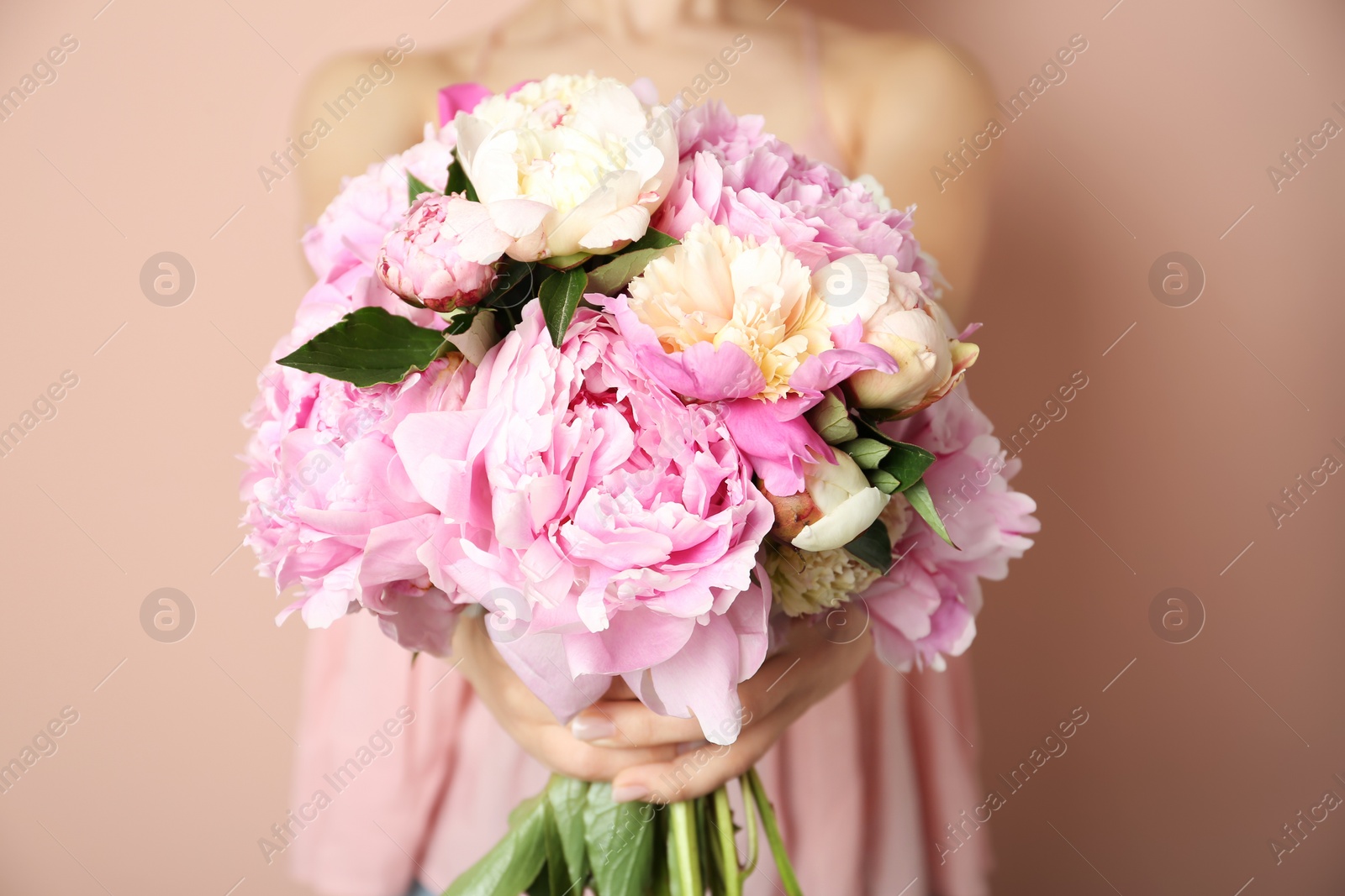 Photo of Woman with bouquet of beautiful peonies on beige background, closeup