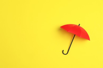 Bright toy umbrella on yellow background, top view. Space for text