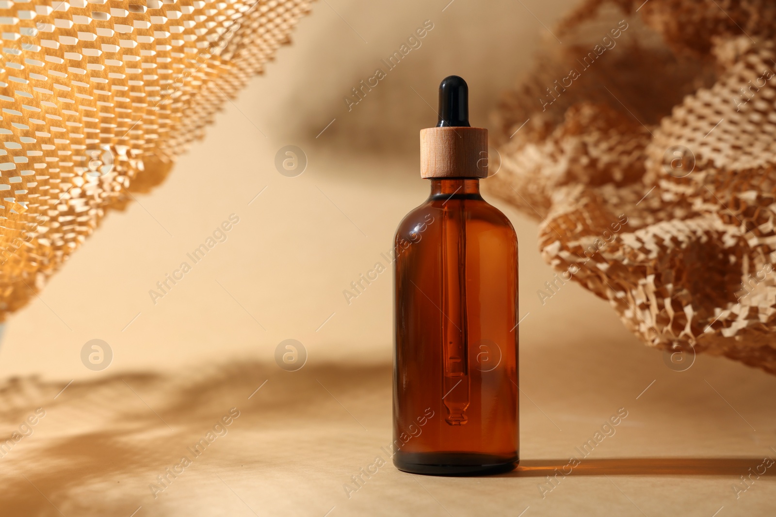 Photo of Glass bottle of essential oil on dark beige background, space for text