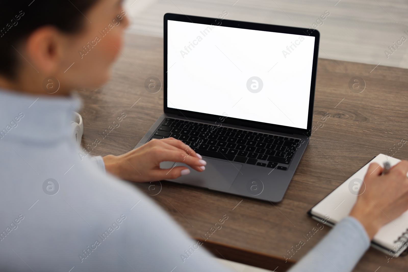 Photo of Young woman writing down notes during webinar at table, closeup