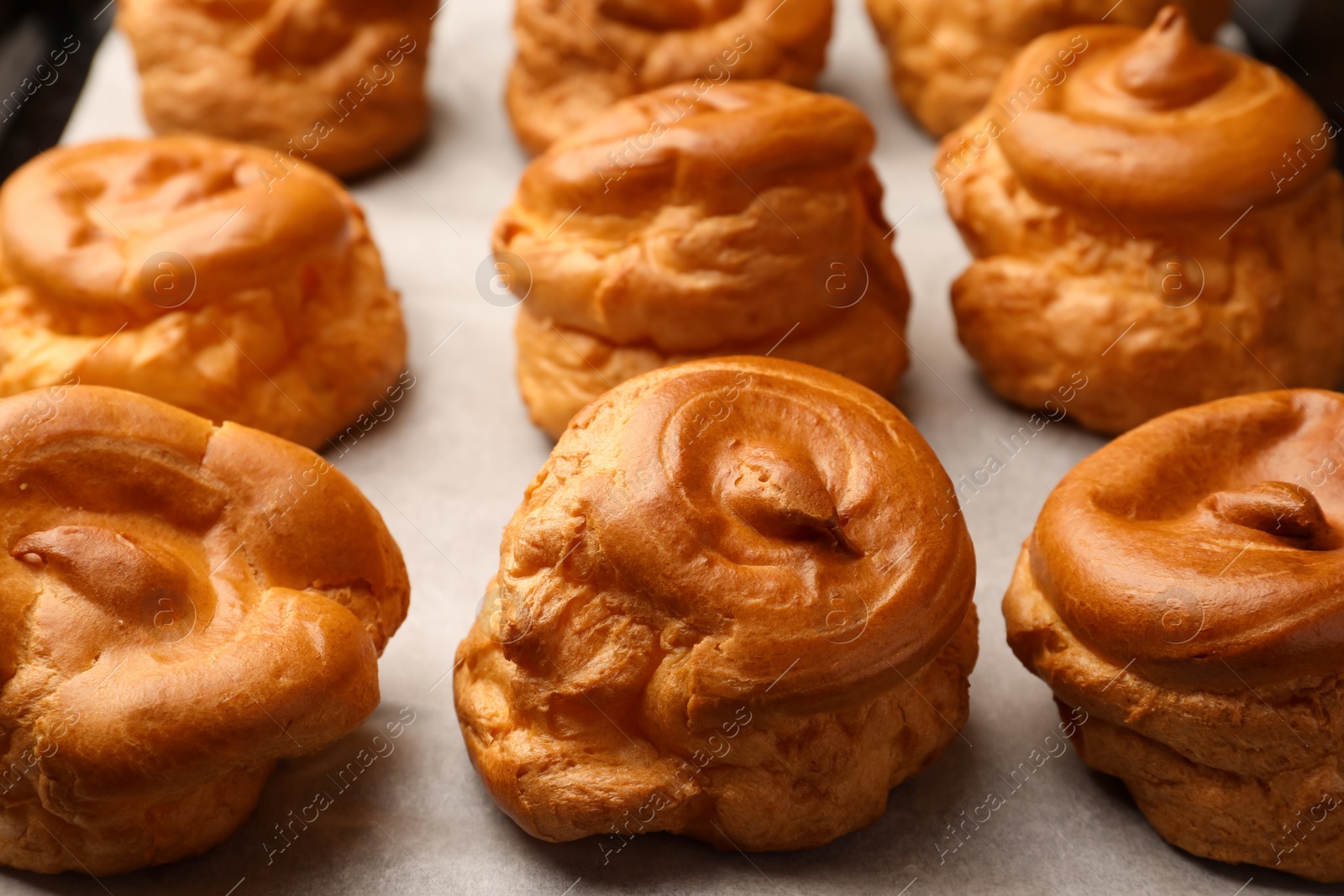 Photo of Delicious fresh profiteroles on baking pan, closeup