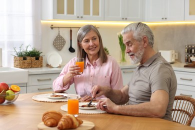 Photo of Happy senior couple having breakfast at home