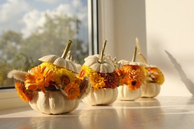 Photo of Small pumpkins with beautiful flowers and spikelets on white wooden window sill indoors