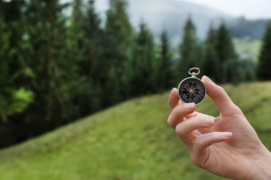 Woman checking modern compass in wilderness, closeup with space for text