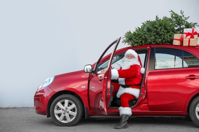Authentic Santa Claus in car with gift boxes and Christmas tree, view from outside