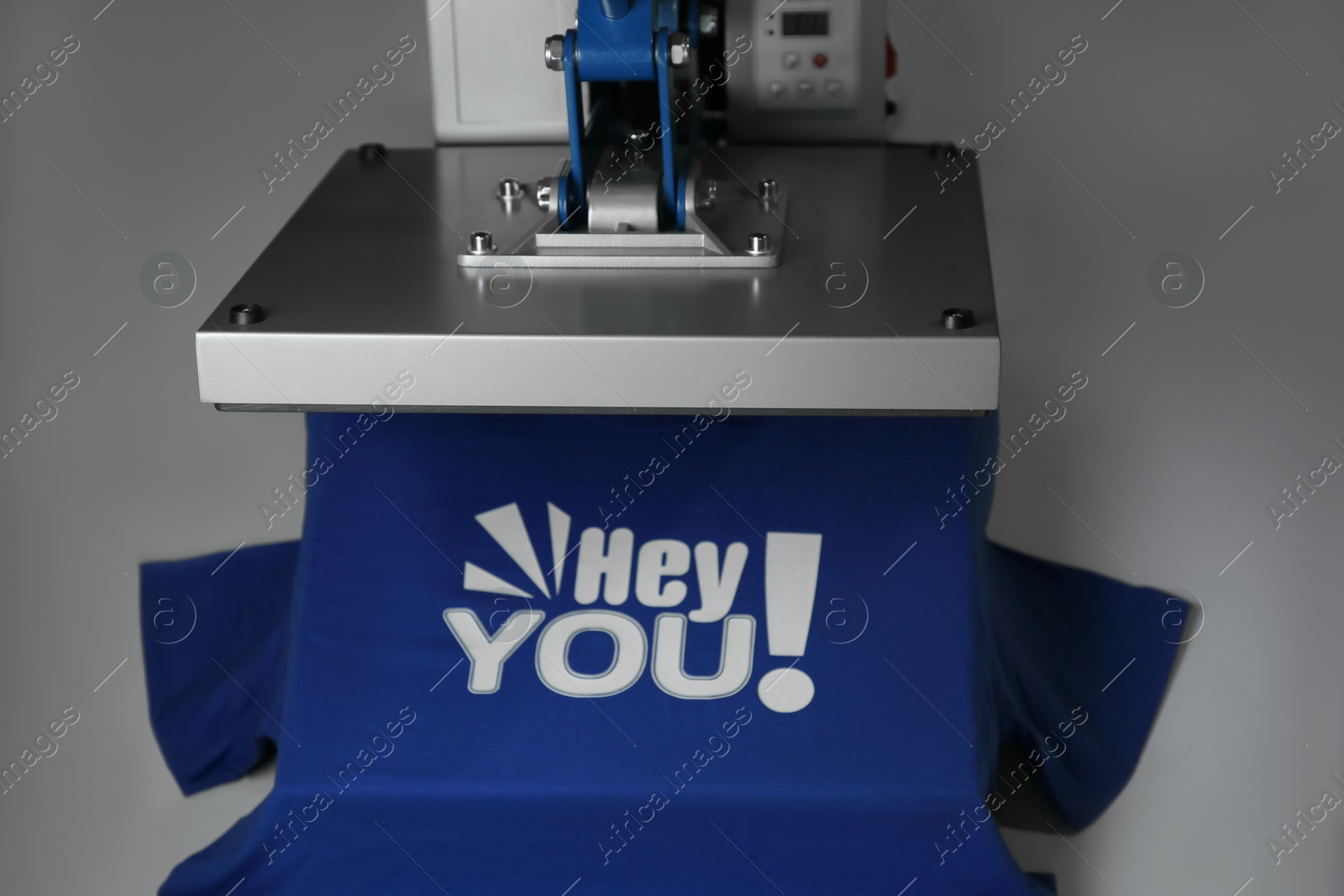 Photo of Printing logo. Heat press with blue t-shirt on white table