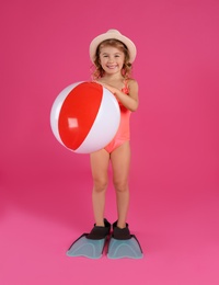 Photo of Cute little child in beachwear with bright inflatable ball on pink background