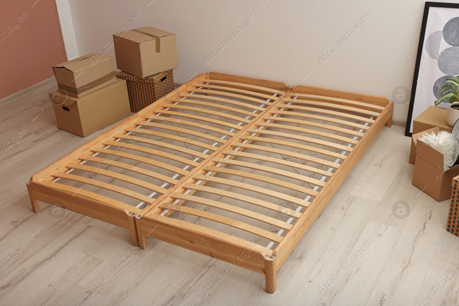 Photo of Wooden bed frame and cardboard boxes on floor in room