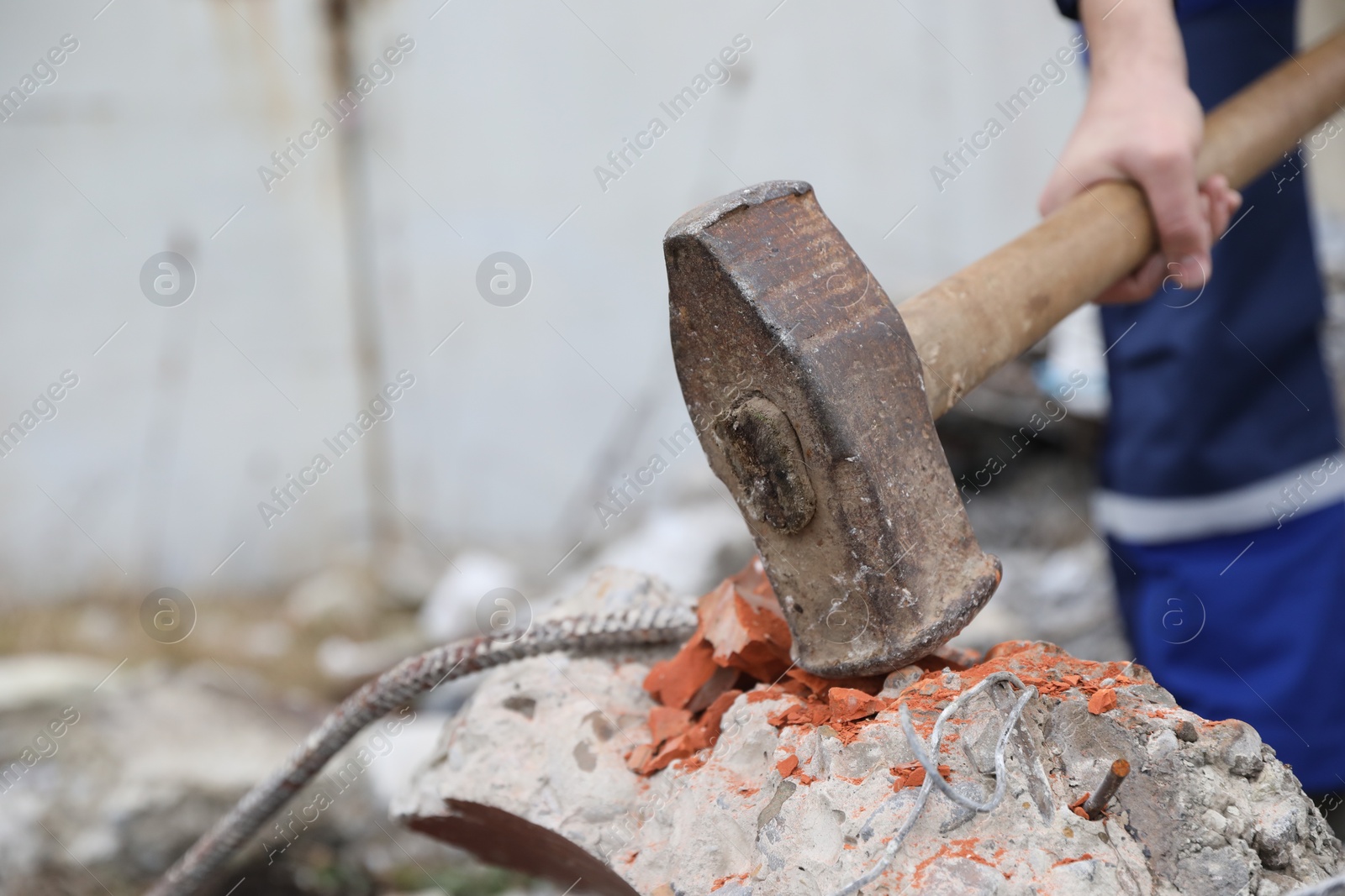 Photo of Man breaking brick with sledgehammer outdoors, selective focus. Space for text