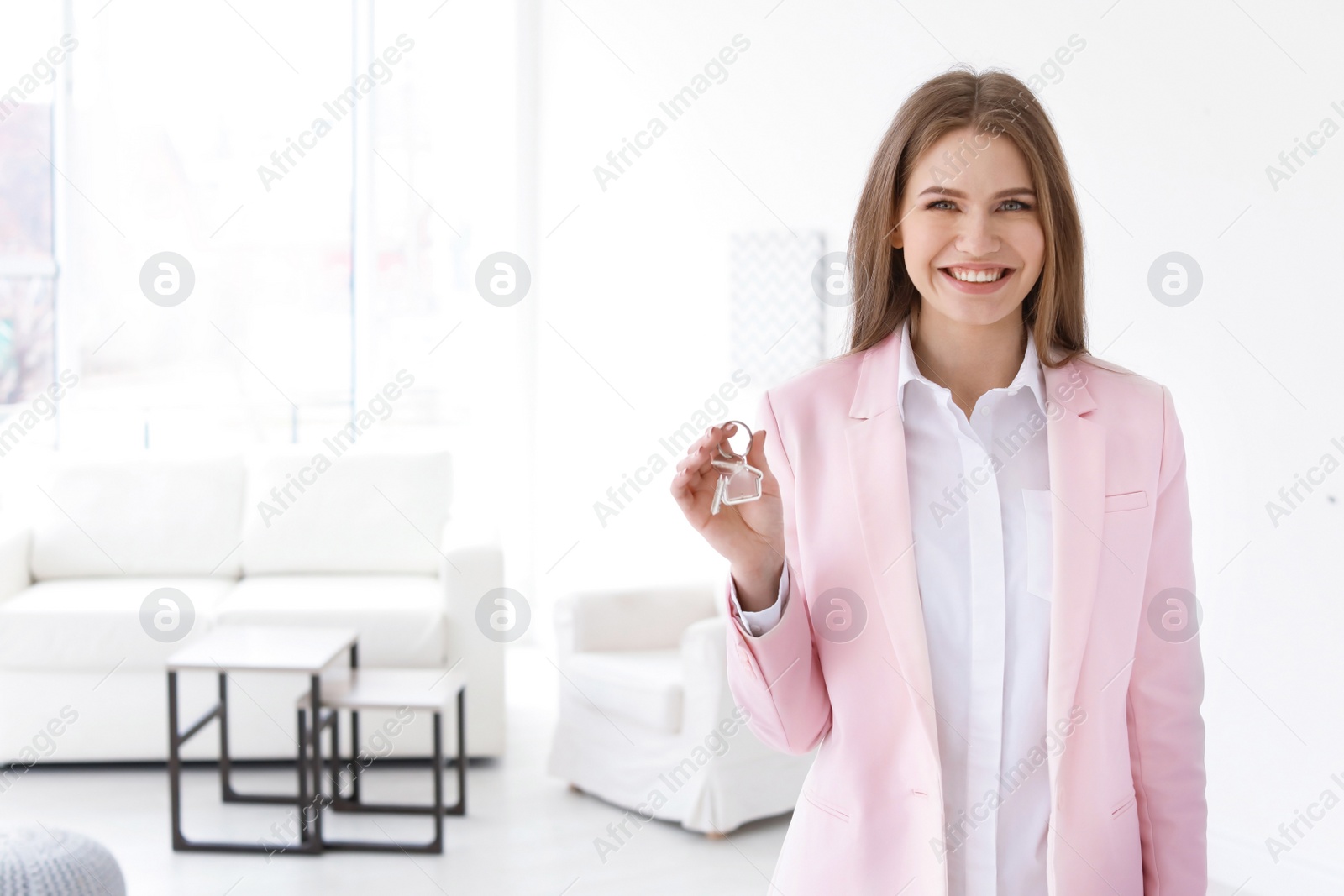 Photo of Beautiful real estate agent with key indoors