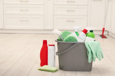 Photo of Different cleaning supplies in bucket on floor. Space for text