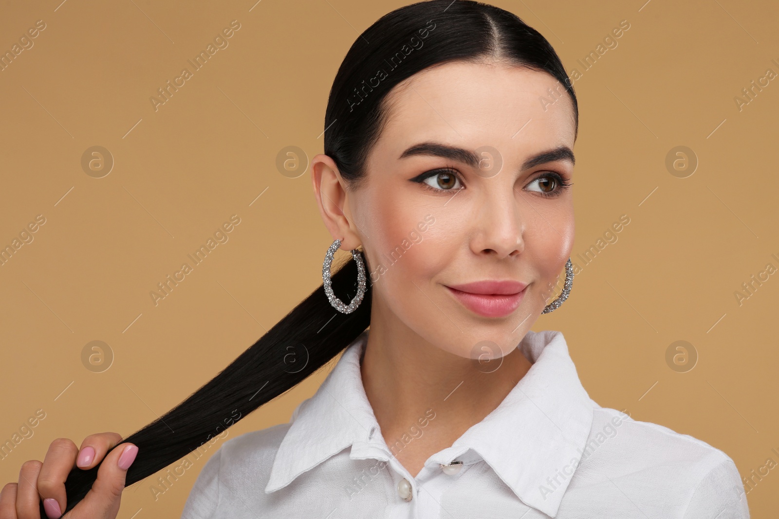 Photo of Beautiful young woman with elegant earrings on beige background