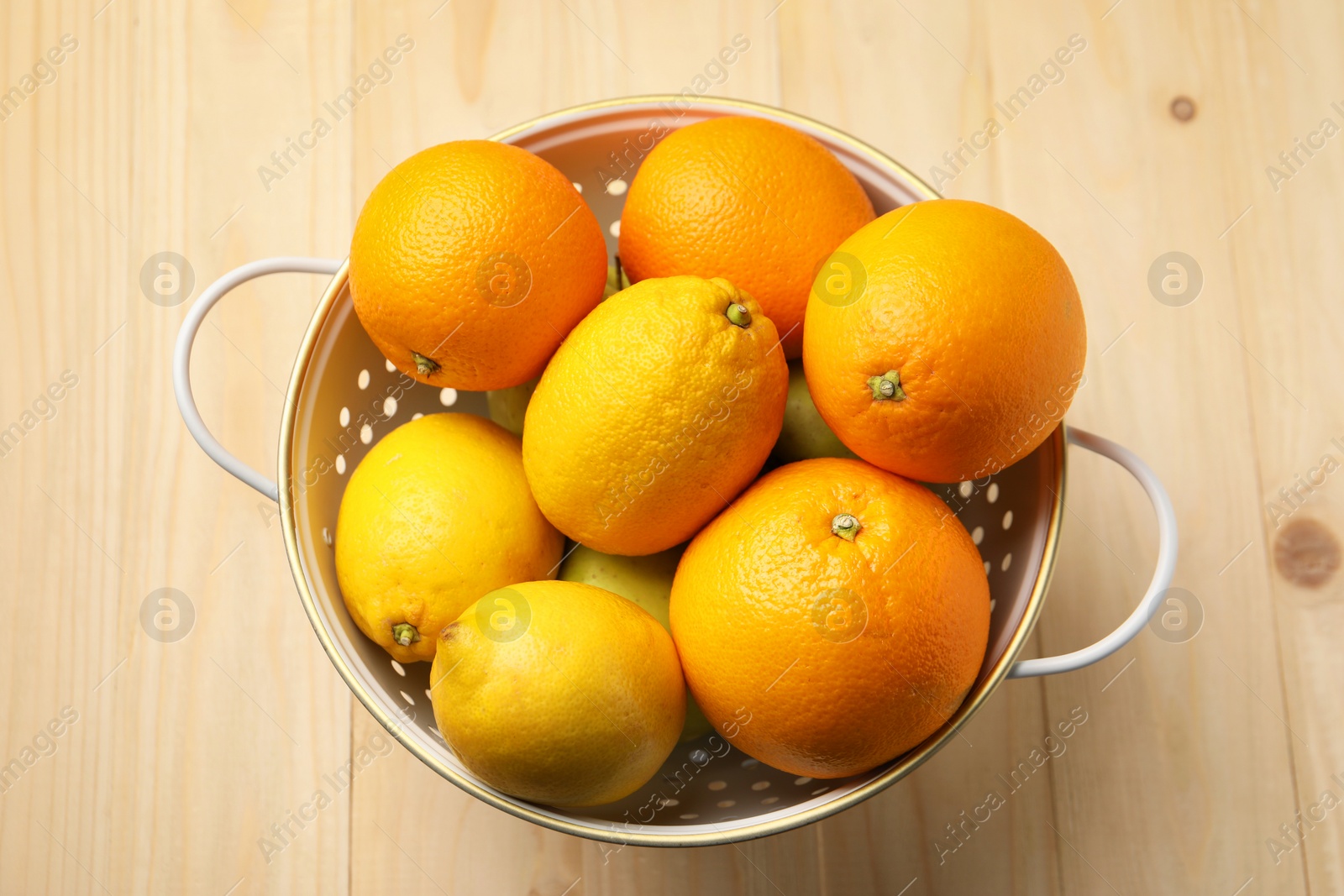 Photo of Colander with fresh citrus fruits on wooden table, top view