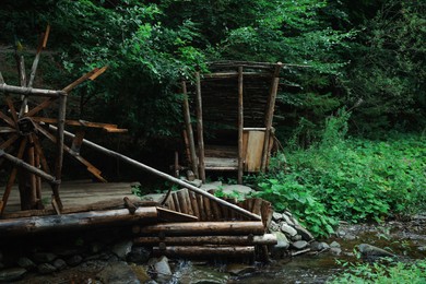 Beautiful wooden water wheel near river in forest